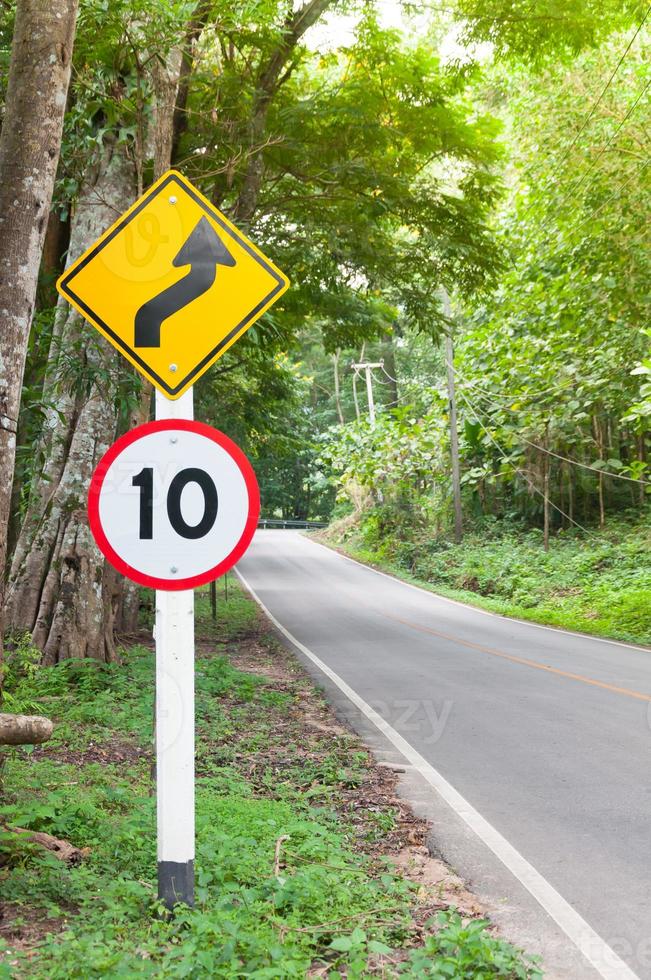 Selective speed limit traffic sign 10 and winding road caution symbol for safety drive in country road in mountain view forest,low key photo