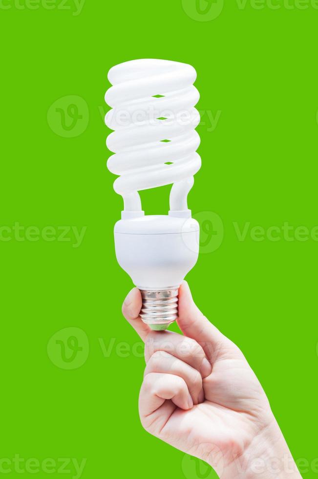 Energy saving concept. Woman hand holding light bulb on green background photo
