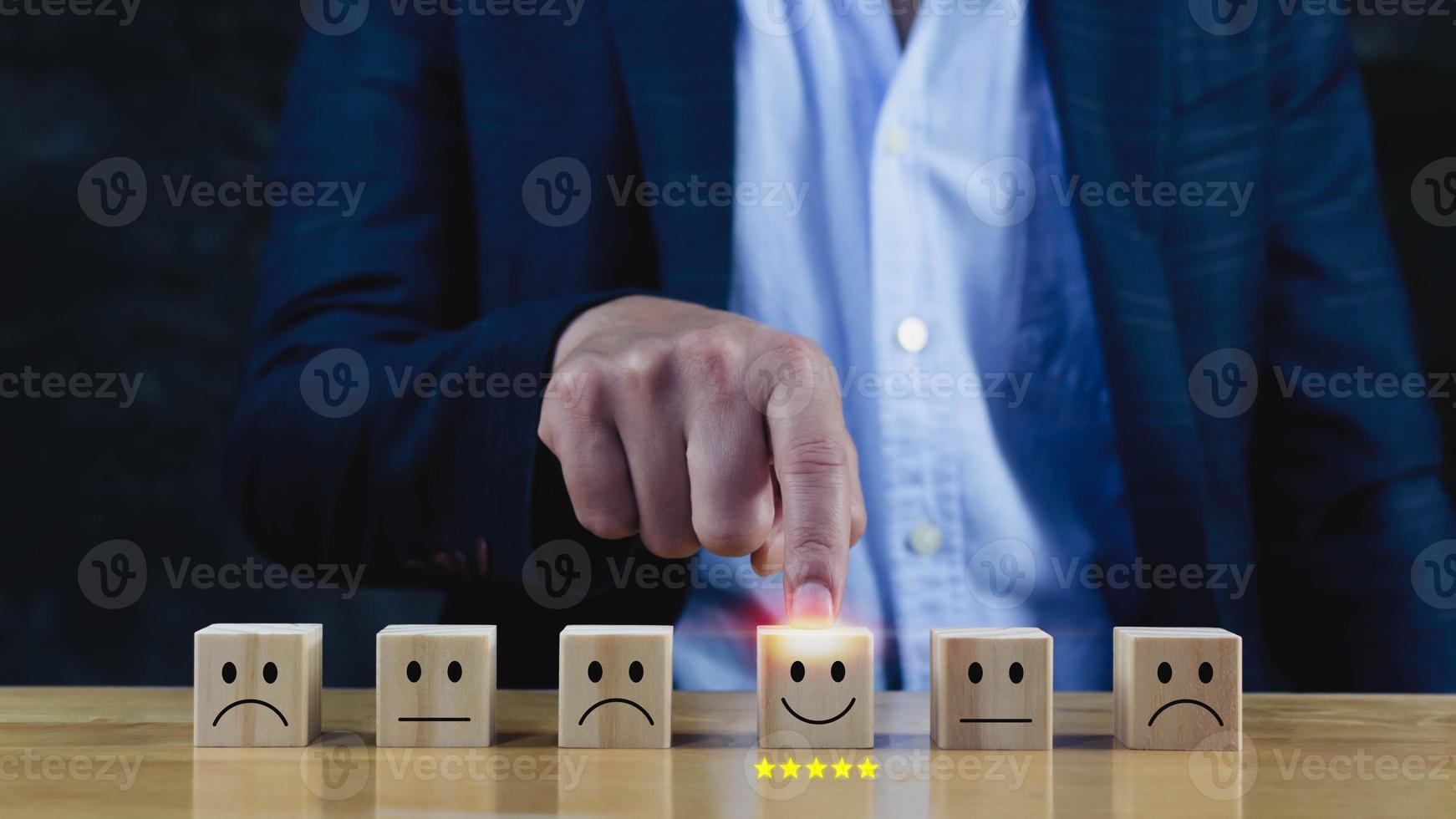 Customer service evaluation and satisfaction survey service rating concepts.Businessman hand choose the wooden block with the happy face smile face icon on wooden cube. photo