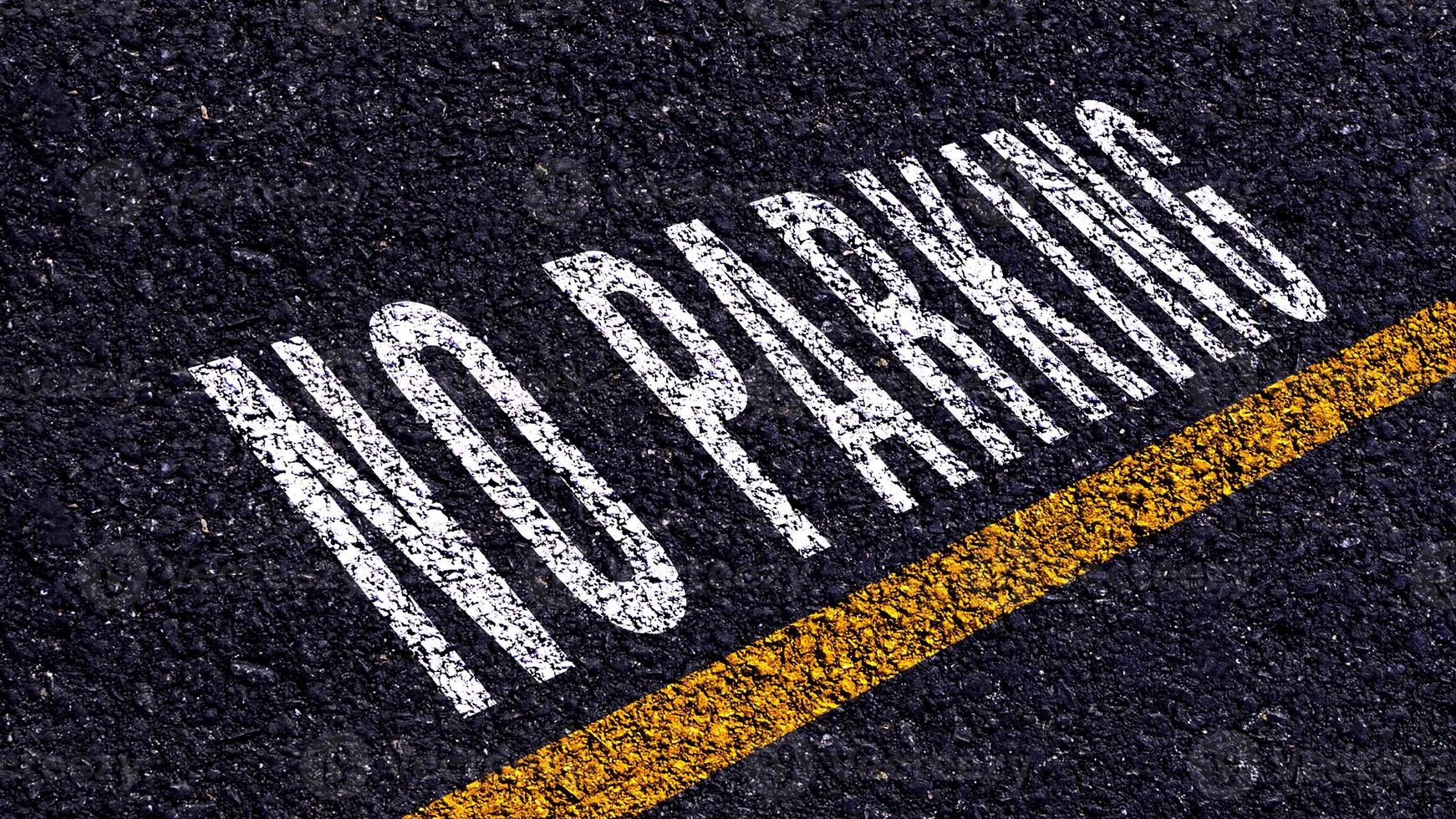 No estacionamiento escrito y amarillo línea en el la carretera en medio de el asfalto camino, No estacionamiento palabra en calle. foto