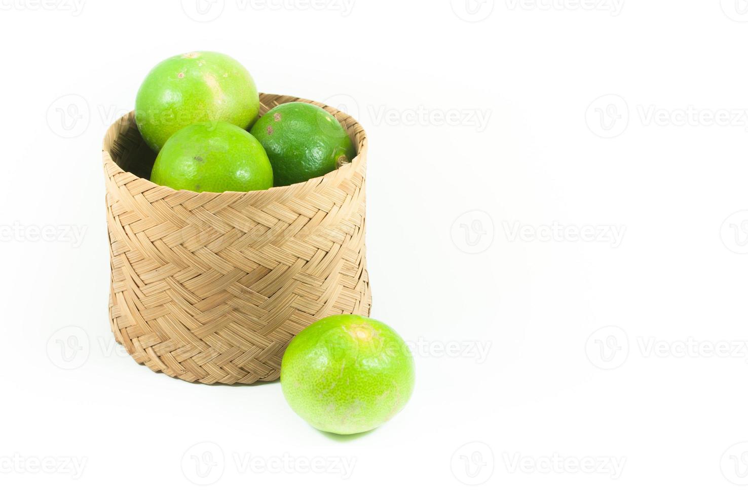 Fresco verde limas en el bambú cesta aislado en blanco fondo, primer plano disparar, Seleccione atención foto
