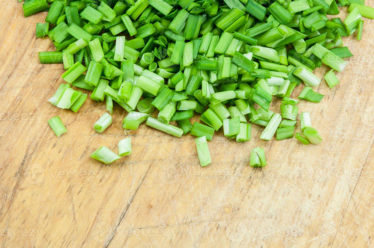 A chopped green onions on a wooden chopping board photo