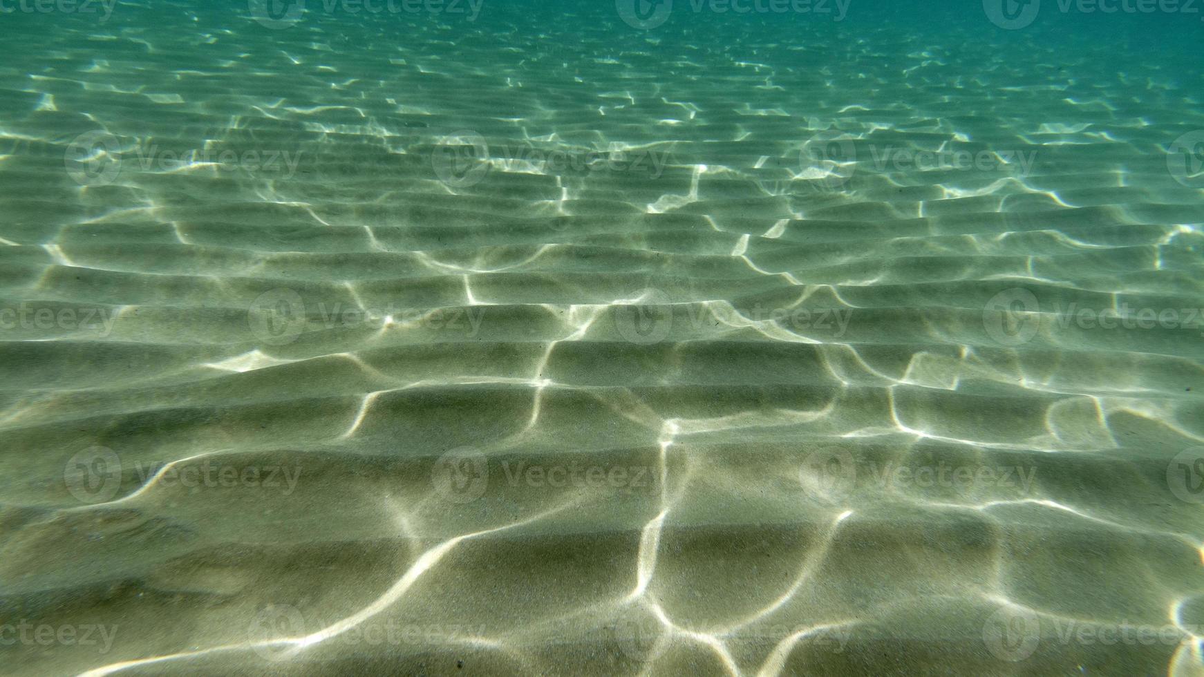 fondo de arena nadando bajo el agua en la laguna turquesa foto