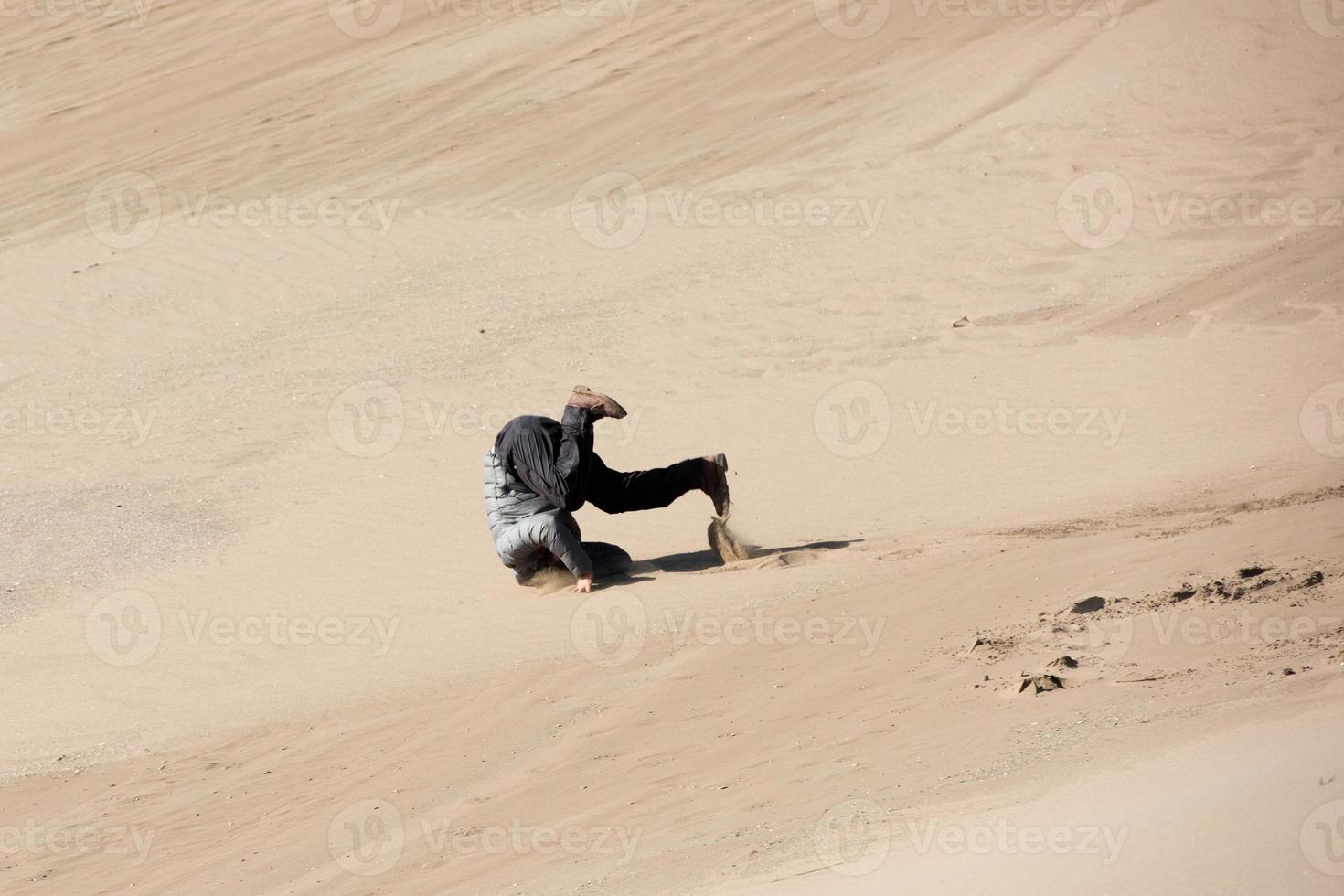 man rolling on sand dunes photo