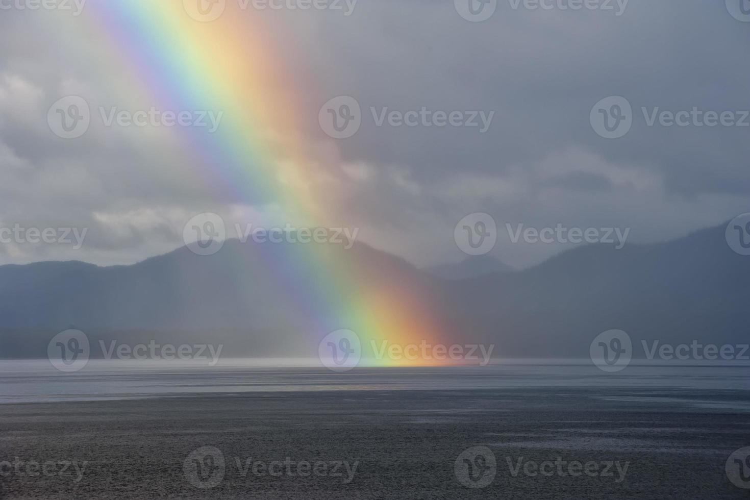 un arco iris cayendo sobre el mar foto