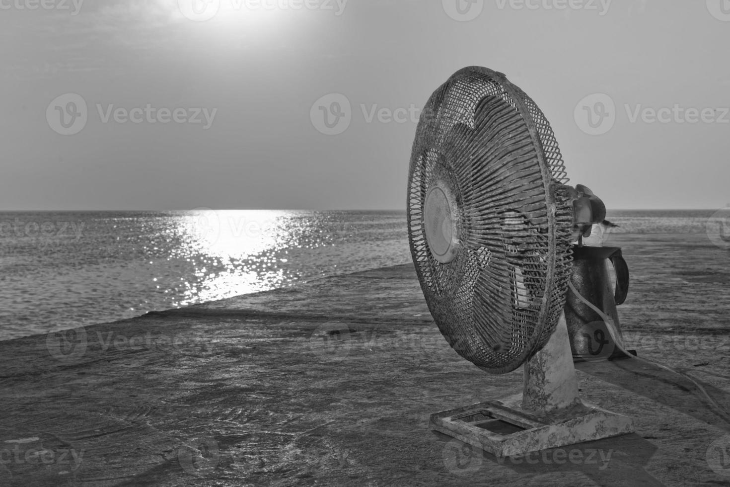 A old used fan near the sea in black and white photo