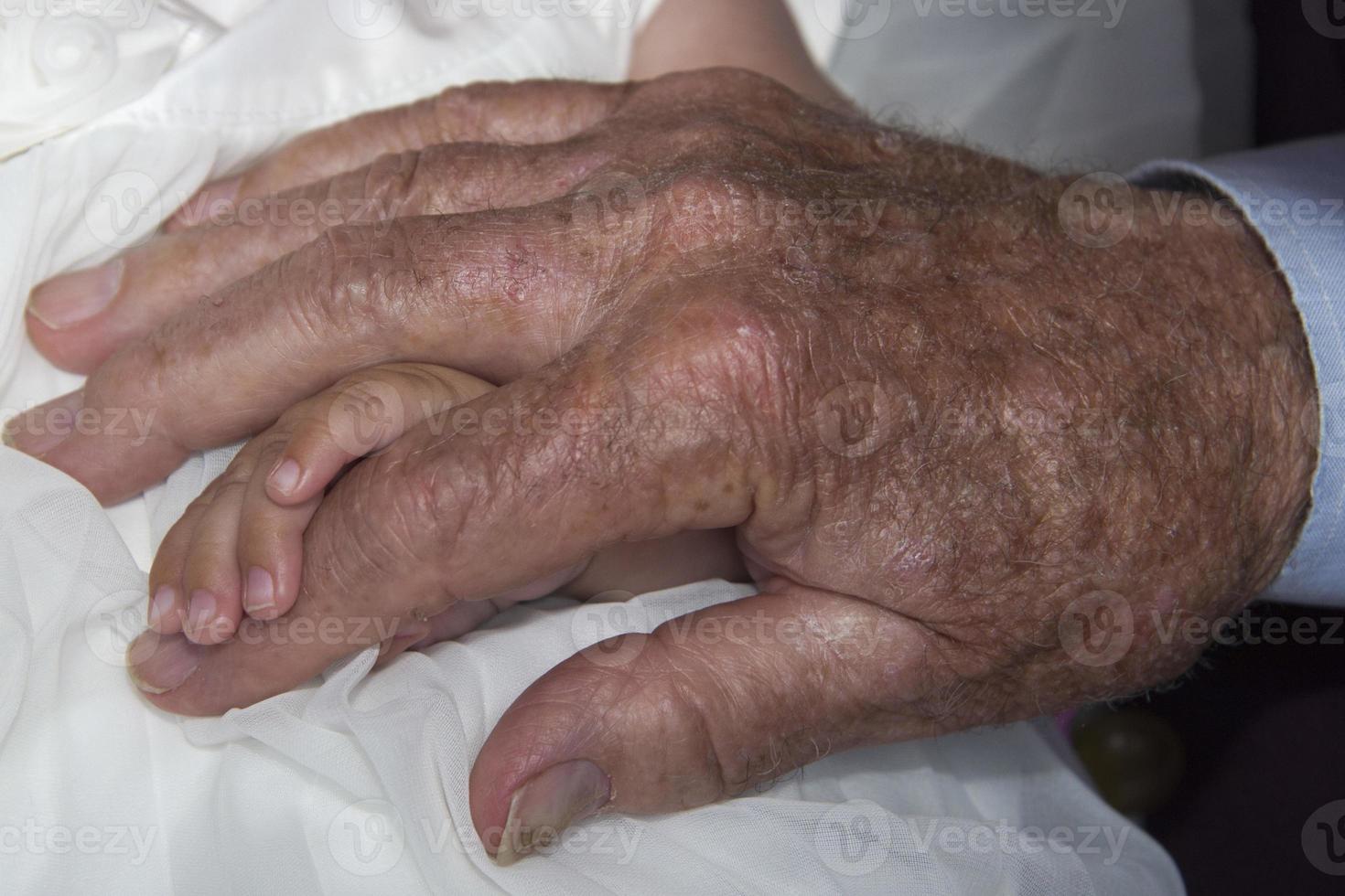 old retired man hands holding newborn infant one photo