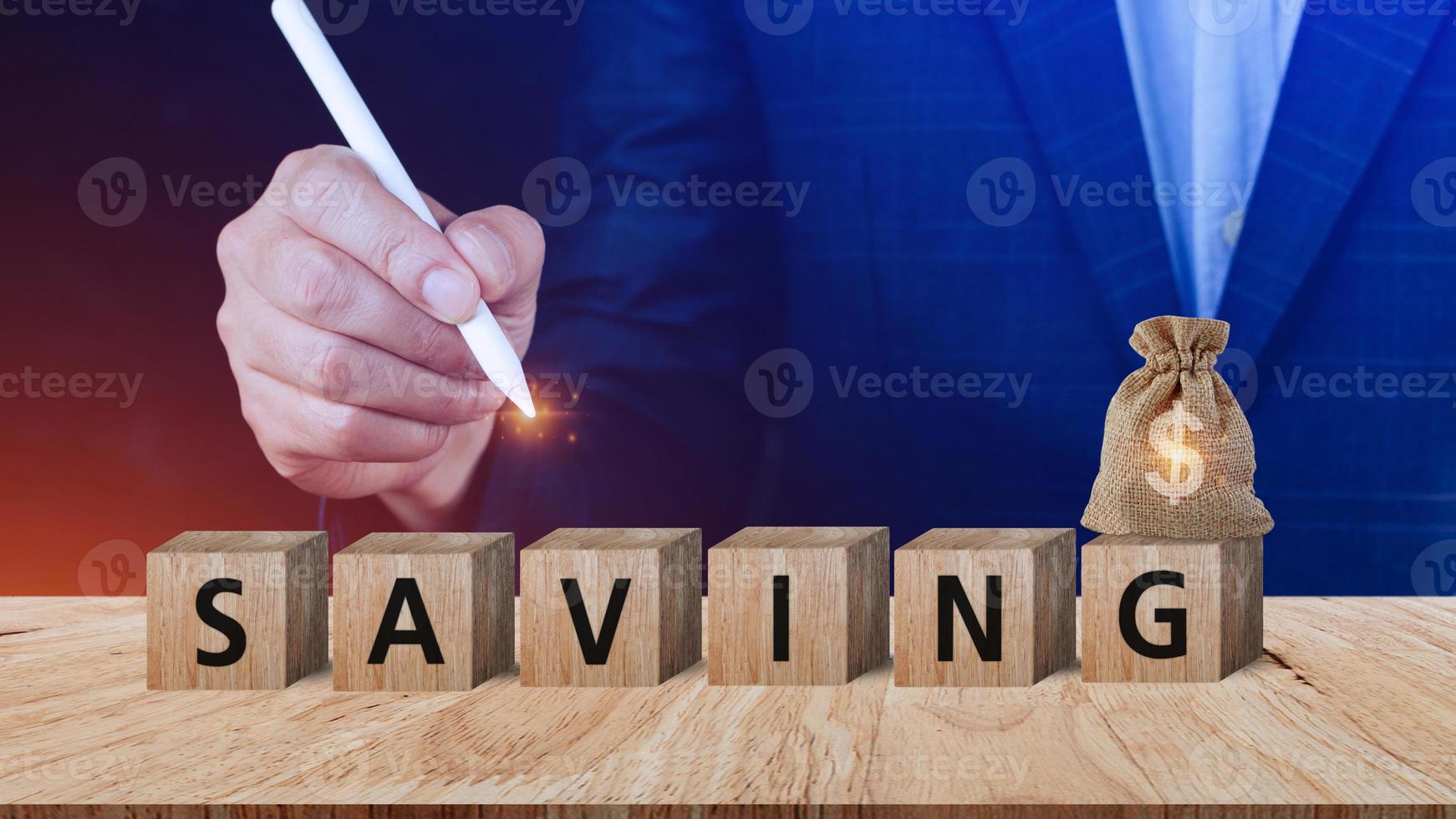 Businessman choose wooden blocks with word saving and US dollar money bag for investment loan planned future concept. saving, charity, family finance plan concept, fundraising, superannuation photo