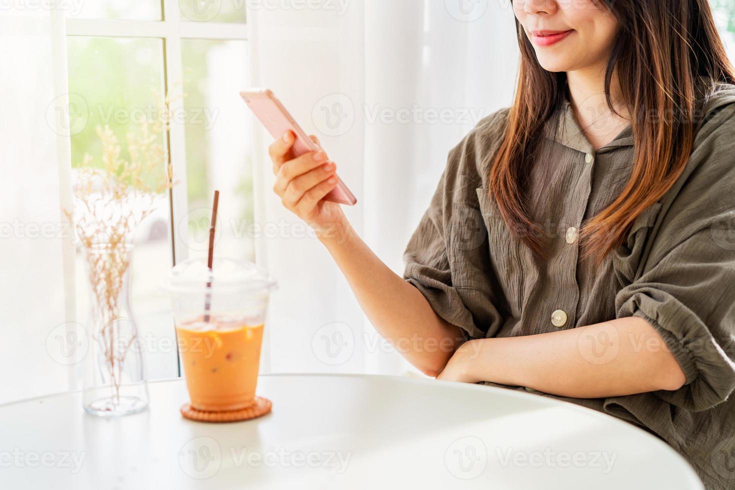 Young woman with drinks using mobile phone and relaxing in cafe, Modern lifestyle photo