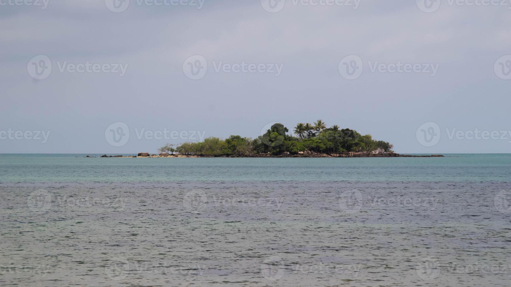 An island across the sea not so far with a lot of tree and green. photo