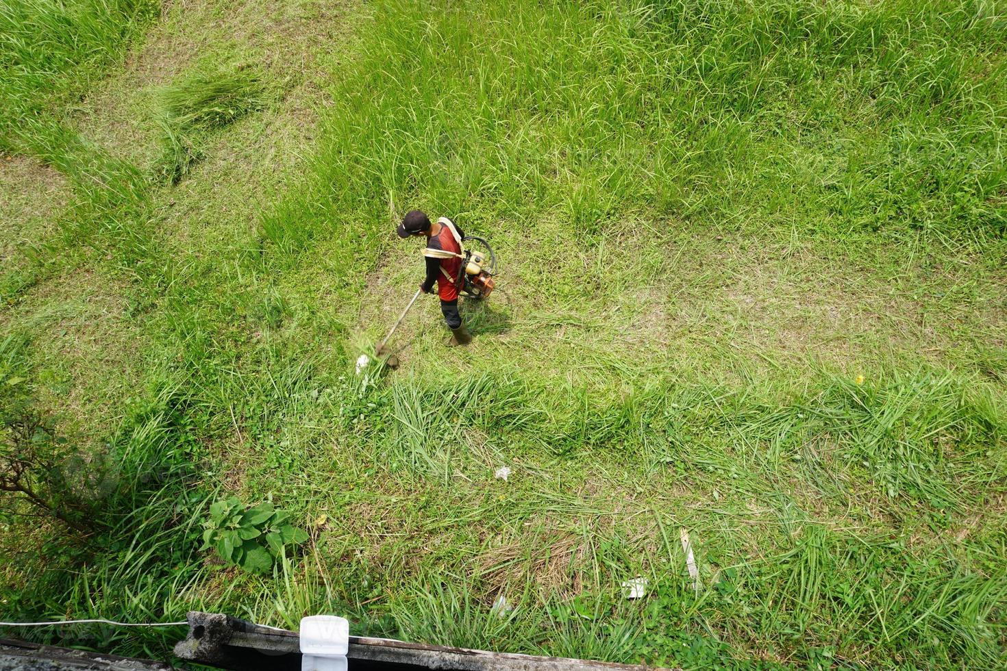 Top view of a man in a robe mowing the grass with a trimmer photo