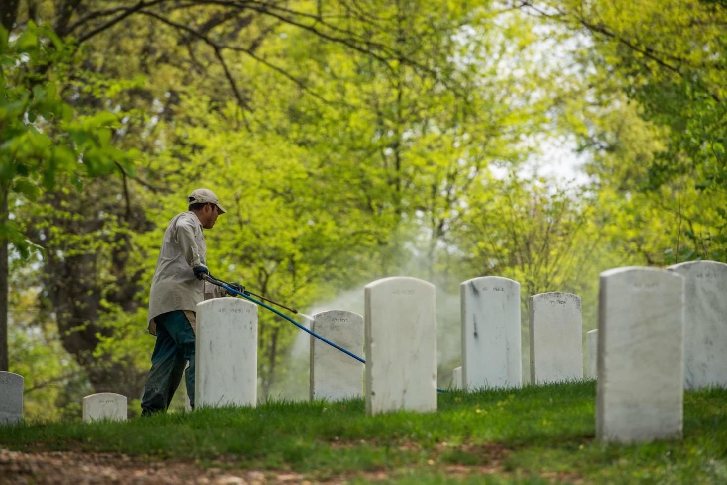 Washington DC, EE.UU. - 2 de mayo de 2014 - el trabajador está limpiando lápidas en el cementerio de Arlington foto