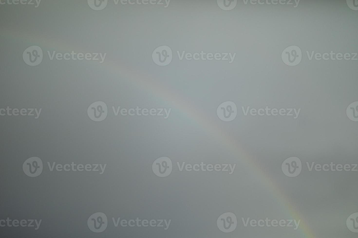 Rainbow in sky. Faint glow of rainbow. Grey sky and bright streaks. photo