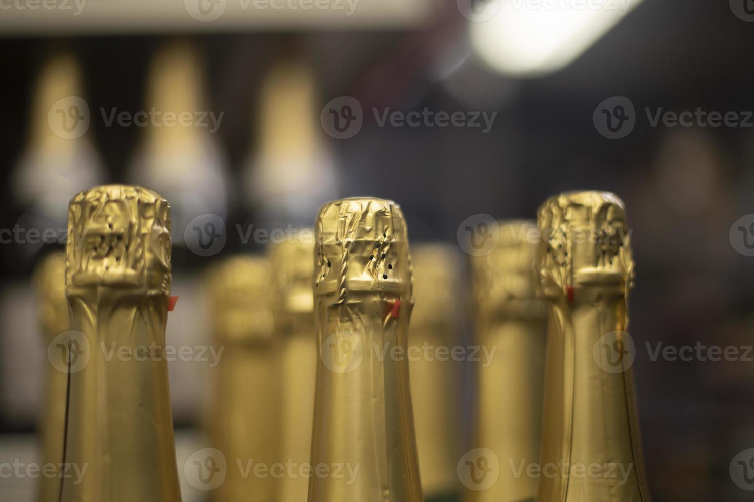 Champagne with gold foil. Bottles of wine in store. Alcoholic beverage stands in row. photo