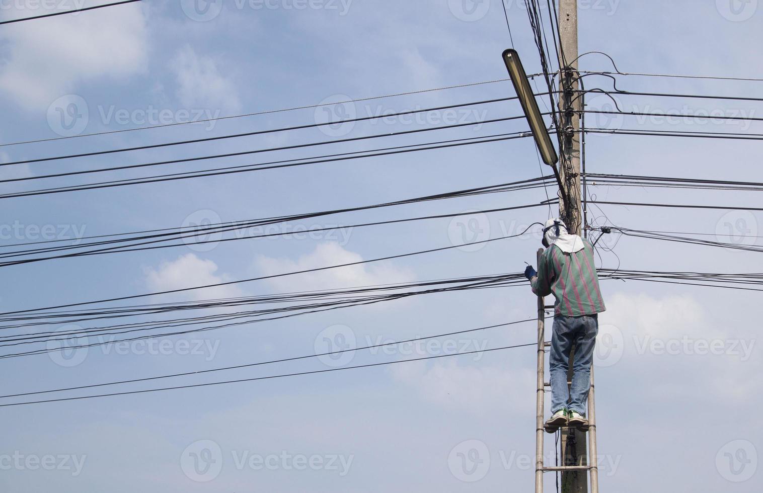 reparar el cable de señal de internet con escaleras de bambú que son muy riesgosas. foto