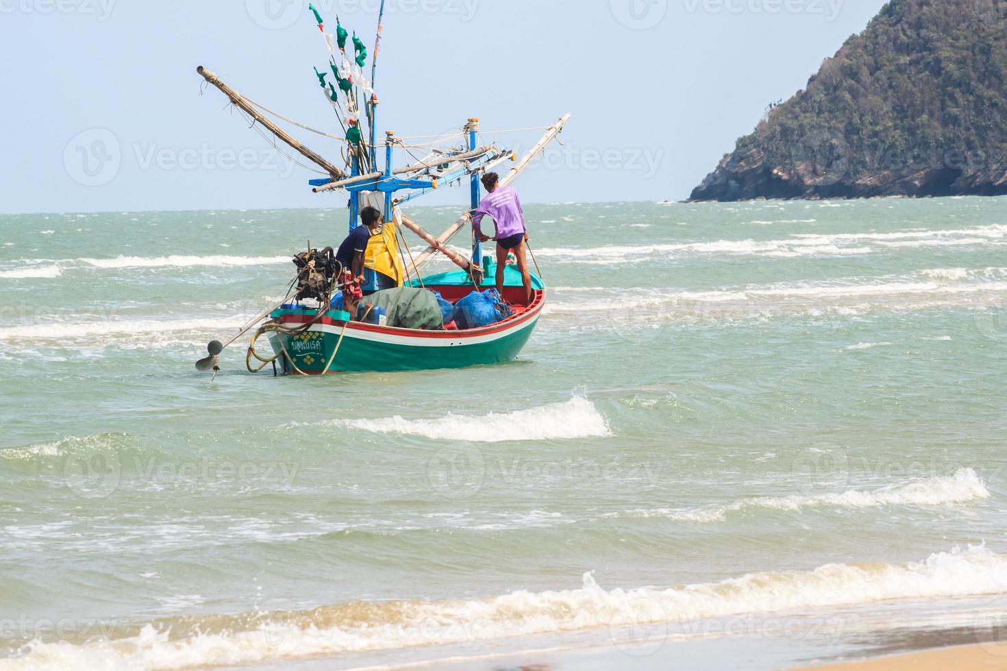 Small fishing boats are mooring at the coast and selling the marine animals they find at The seaside where the waves are always windy. The boat is made of hardwood throughout the hull. photo