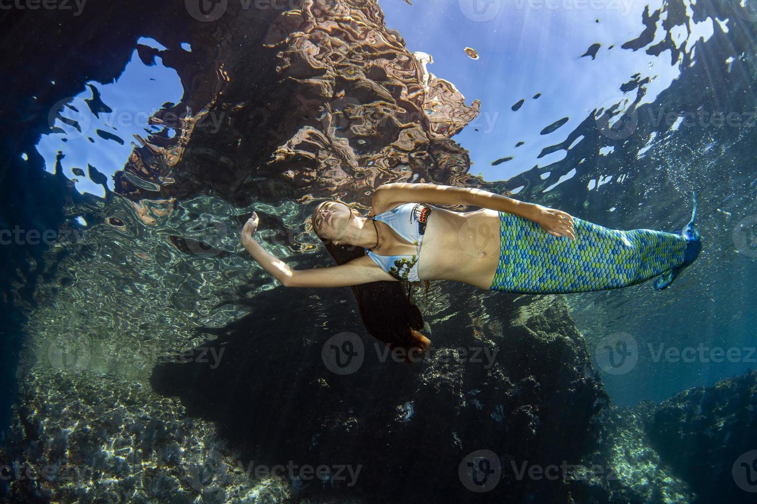 Mermaid swimming underwater in the deep blue sea photo