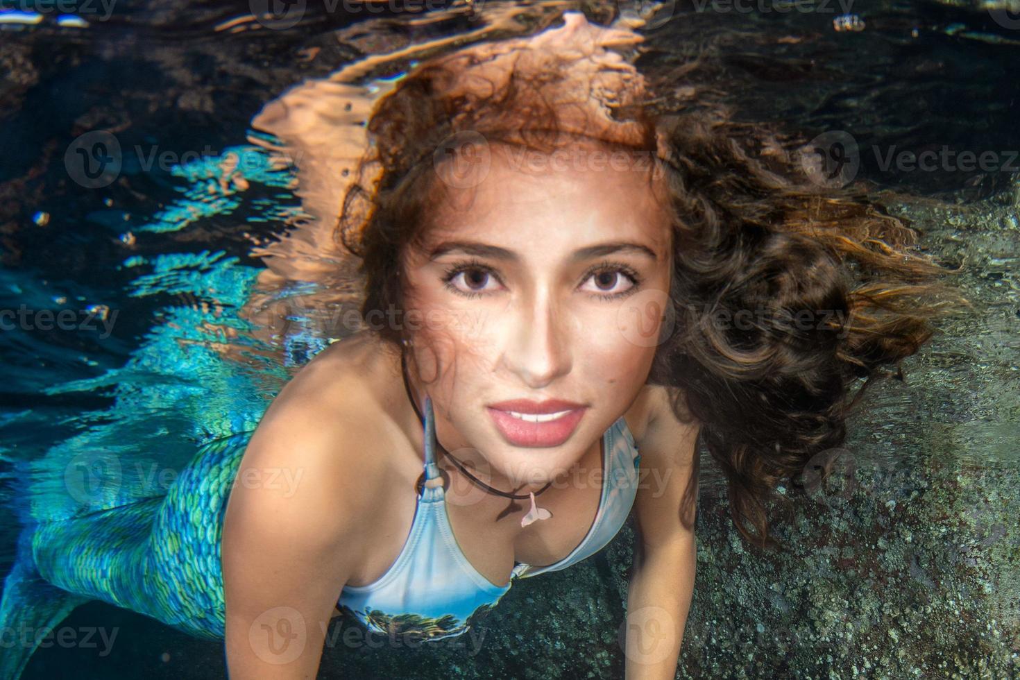 Mermaid swimming underwater in the deep blue sea photo