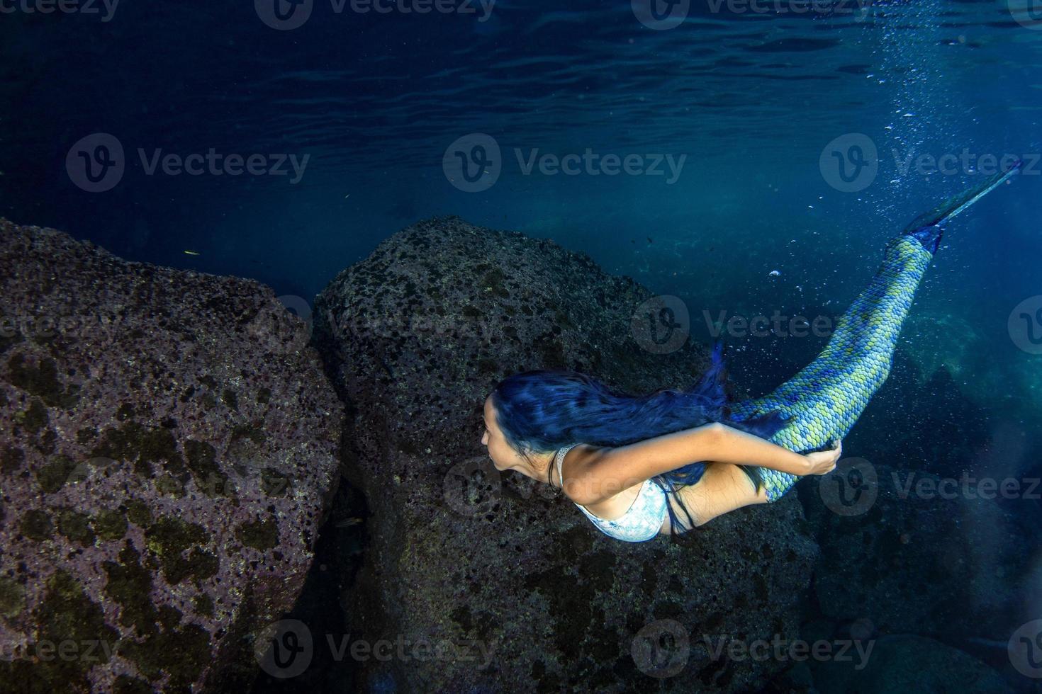 sirena nadando bajo el agua en el mar azul profundo foto