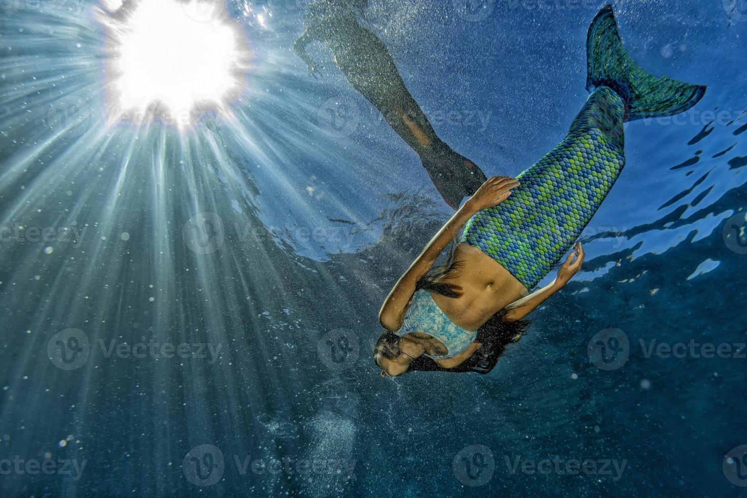 two Mermaid swimming underwater in the deep blue sea photo