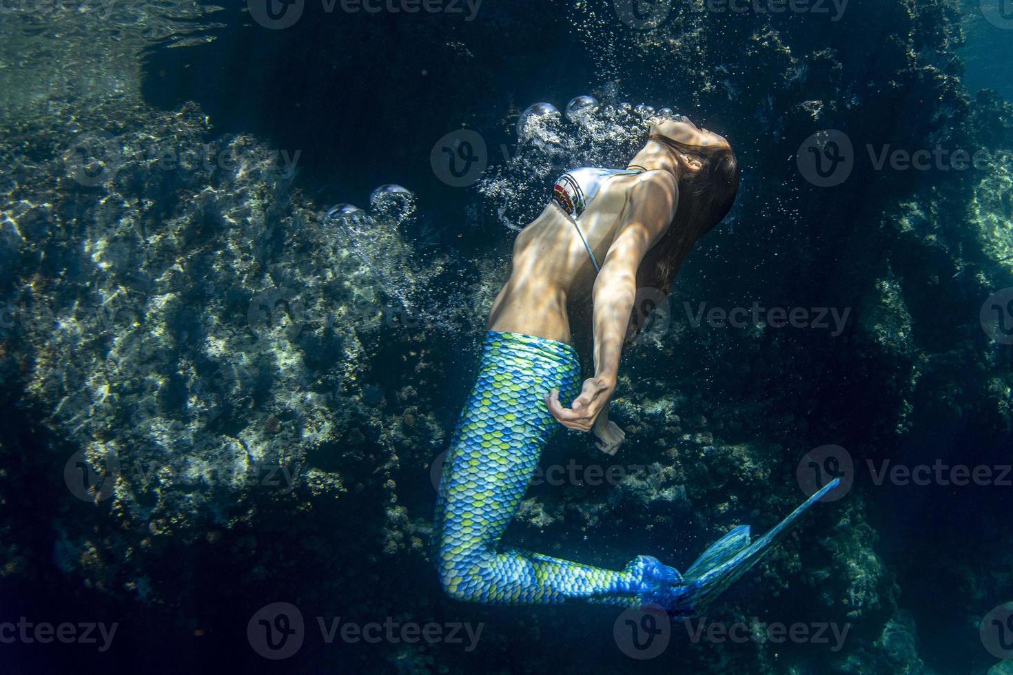 sirena nadando bajo el agua en el mar azul profundo foto