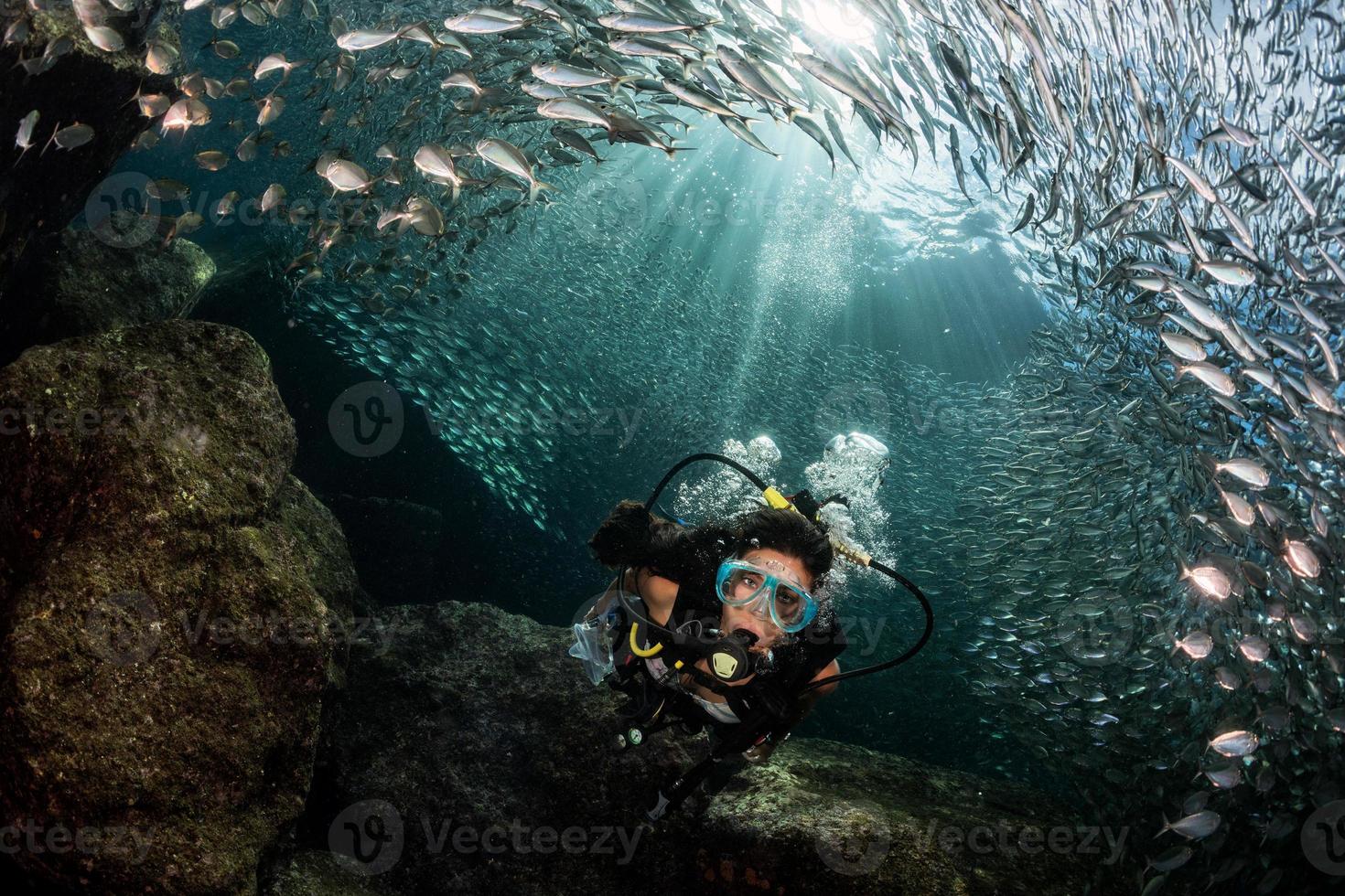 Hermosa buceadora latina dentro de un banco de peces. foto