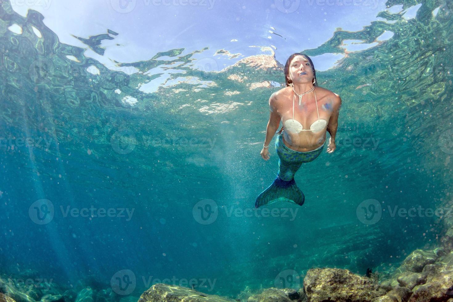 Mermaid swimming underwater in the deep blue sea photo