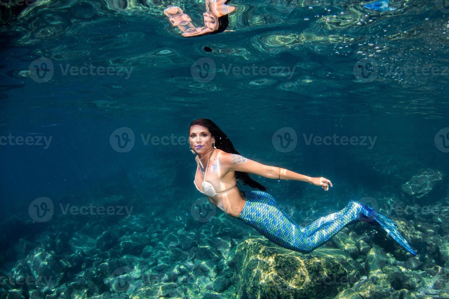 Beautiful Mermaid swimming underwater in the deep blue sea photo