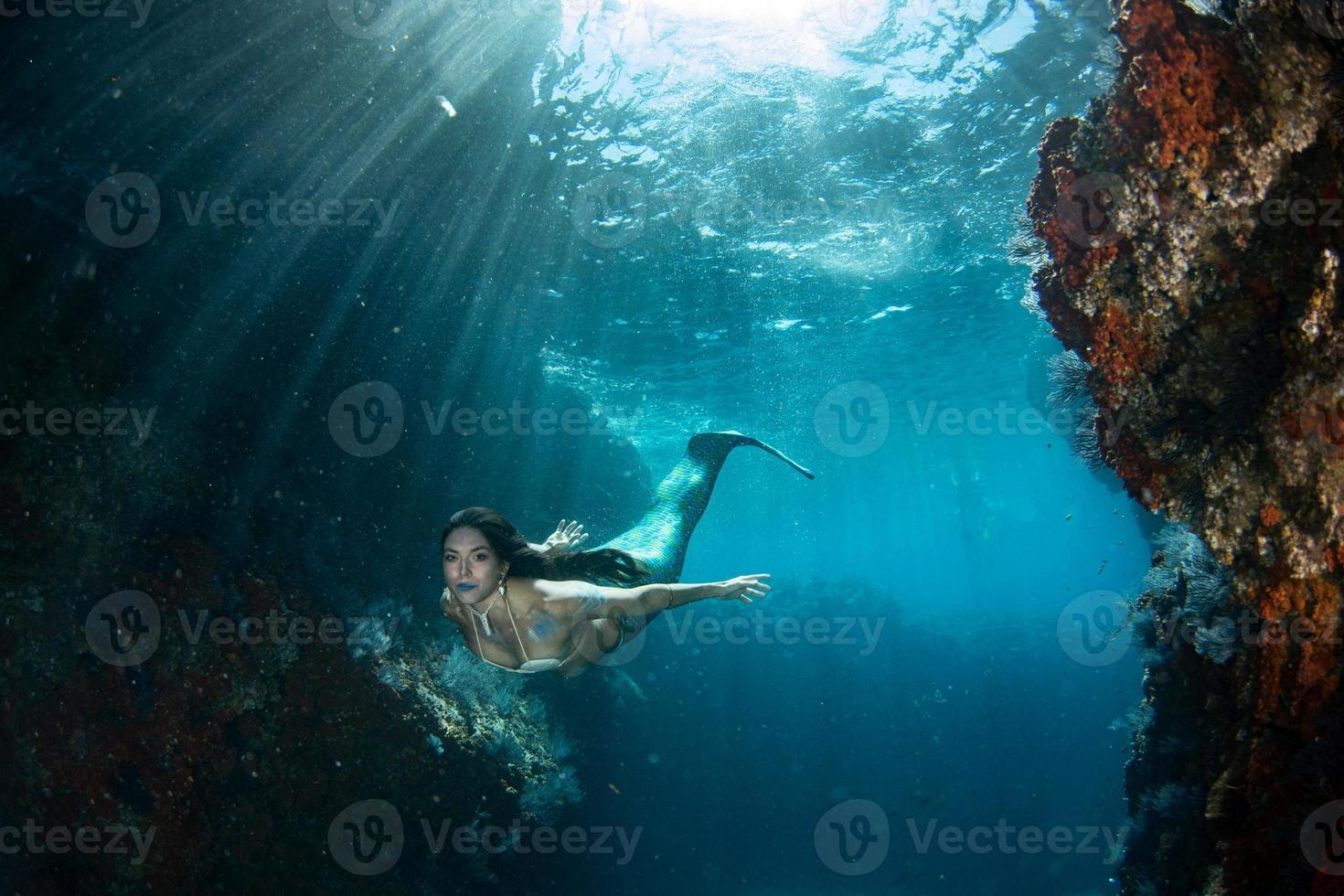 sirena nadando bajo el agua en el mar azul profundo foto