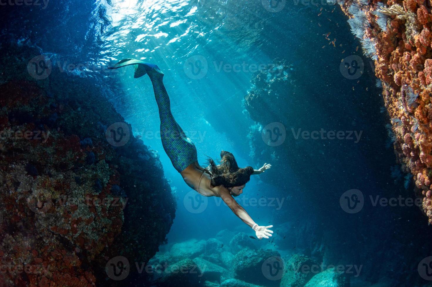 Mermaid swimming underwater in the deep blue sea photo