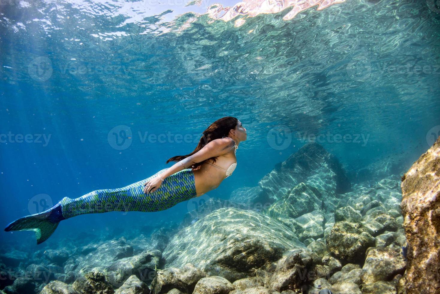 sirena nadando bajo el agua en el mar azul profundo foto