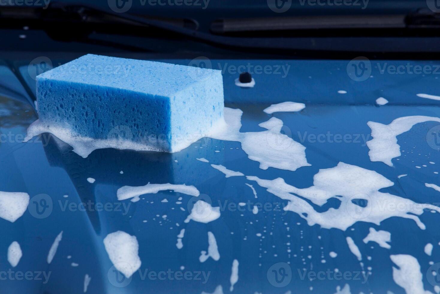 Worker washing car with sponge on a car wash, Manual car wash with