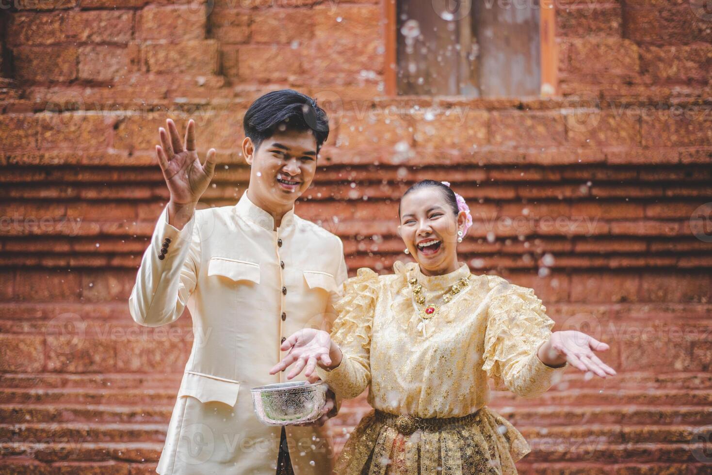 Young couple splashing water from bowl on Songkran festival photo