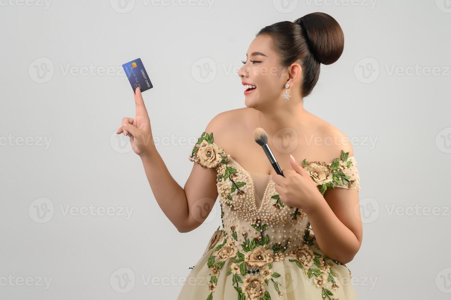 Young asian beautiful bride posting with credit card and beauty brush in hand photo