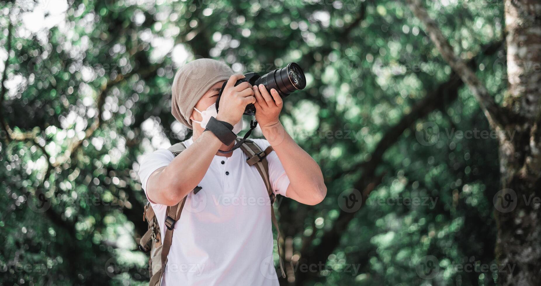 Asian traveler man with backpack taking a photo in the park