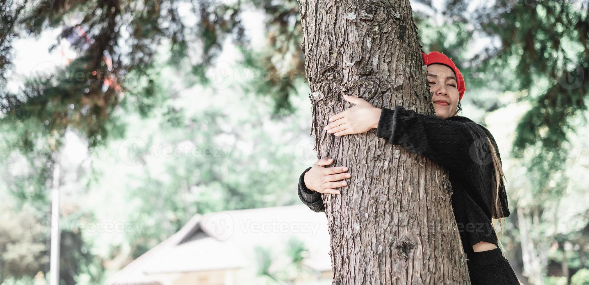 contento joven mujer abrazando un grande árbol con un feliz expresión con Copiar espacio foto