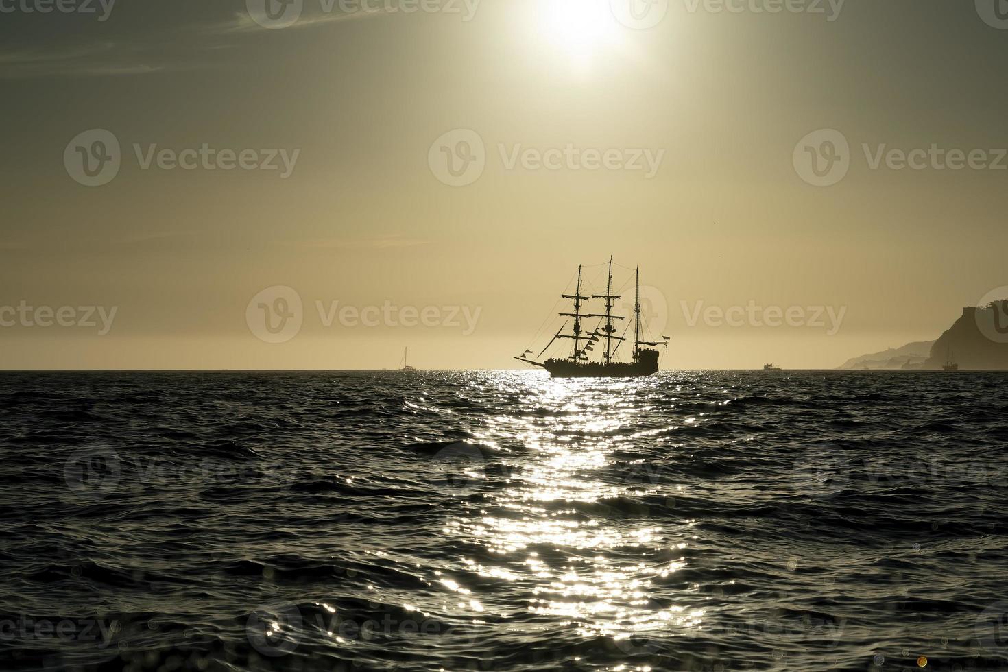 pirate ship silhouette at sunset at the open sea at the sunset photo