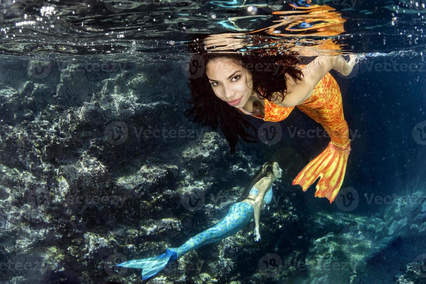 sirena nadando bajo el agua en el mar azul profundo foto