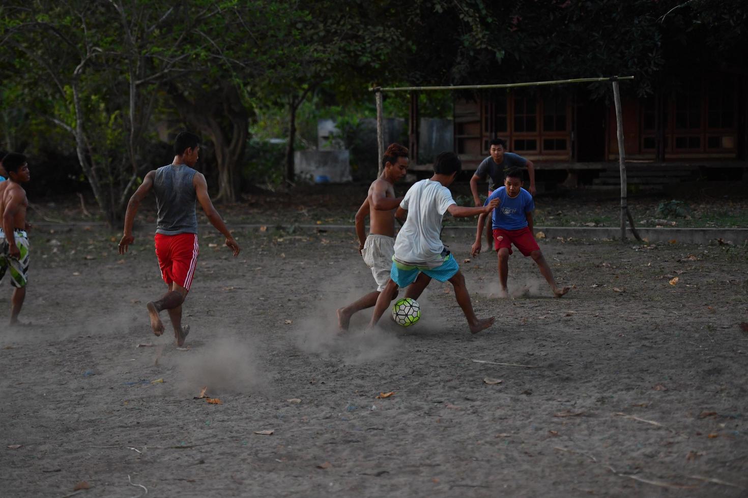 GILI ASAHAN, INDONESIA - AUGUST, 22 2016 - boys are playing soccer at sunset on a palm tree field near the beach photo