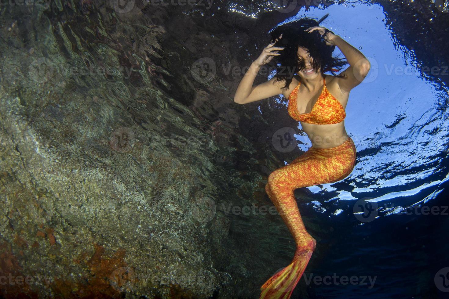 orange tail Mermaid swimming underwater in the deep blue sea photo