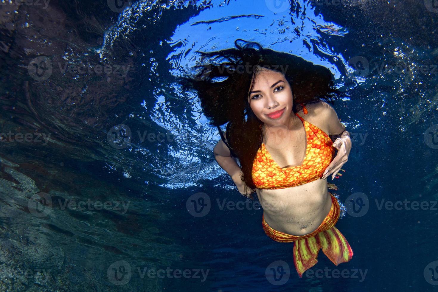 Mermaid swimming underwater in the deep blue sea photo