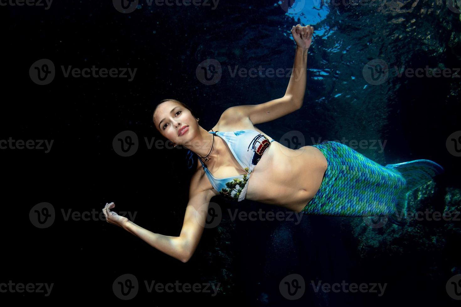 Mermaid swimming underwater in the deep blue sea photo