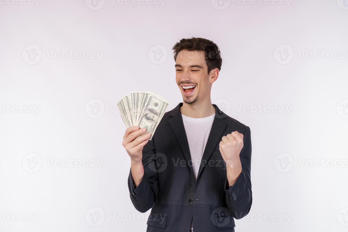 retrato de un hombre alegre que sostiene billetes de dólar y hace gesto de ganador apretando el puño sobre fondo blanco foto