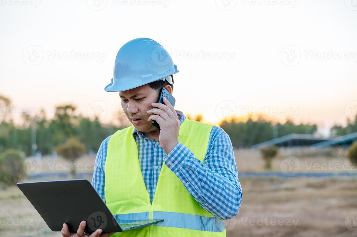 Young engineer use smartphone while working at solar farm photo