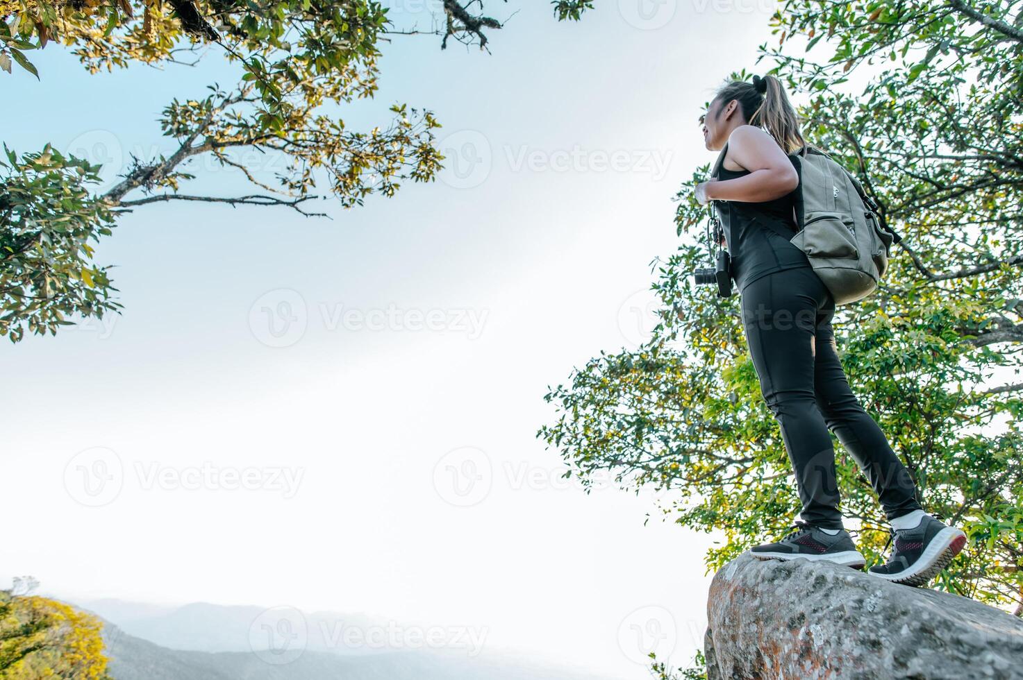 Young hiker woman standing on rocky and looking view photo