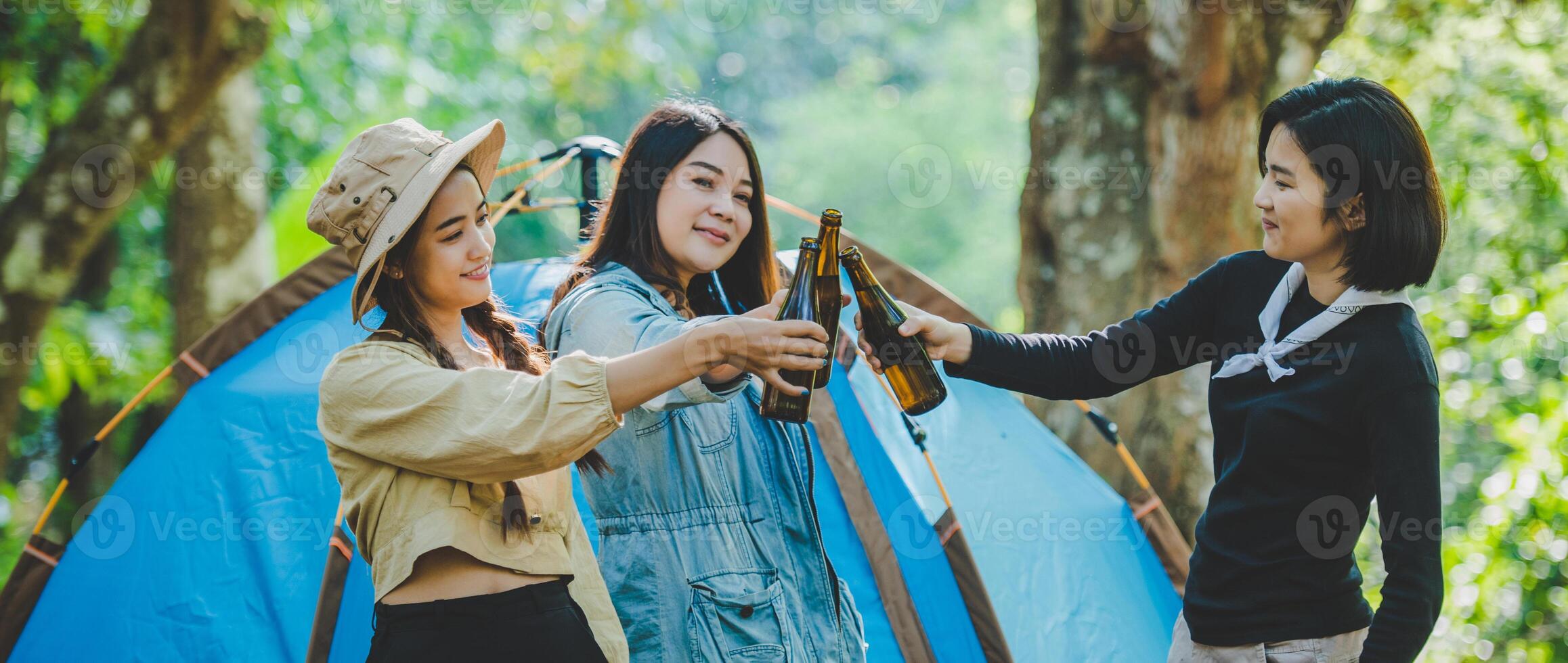 Young woman cheer and drink beverage front of camping tent photo