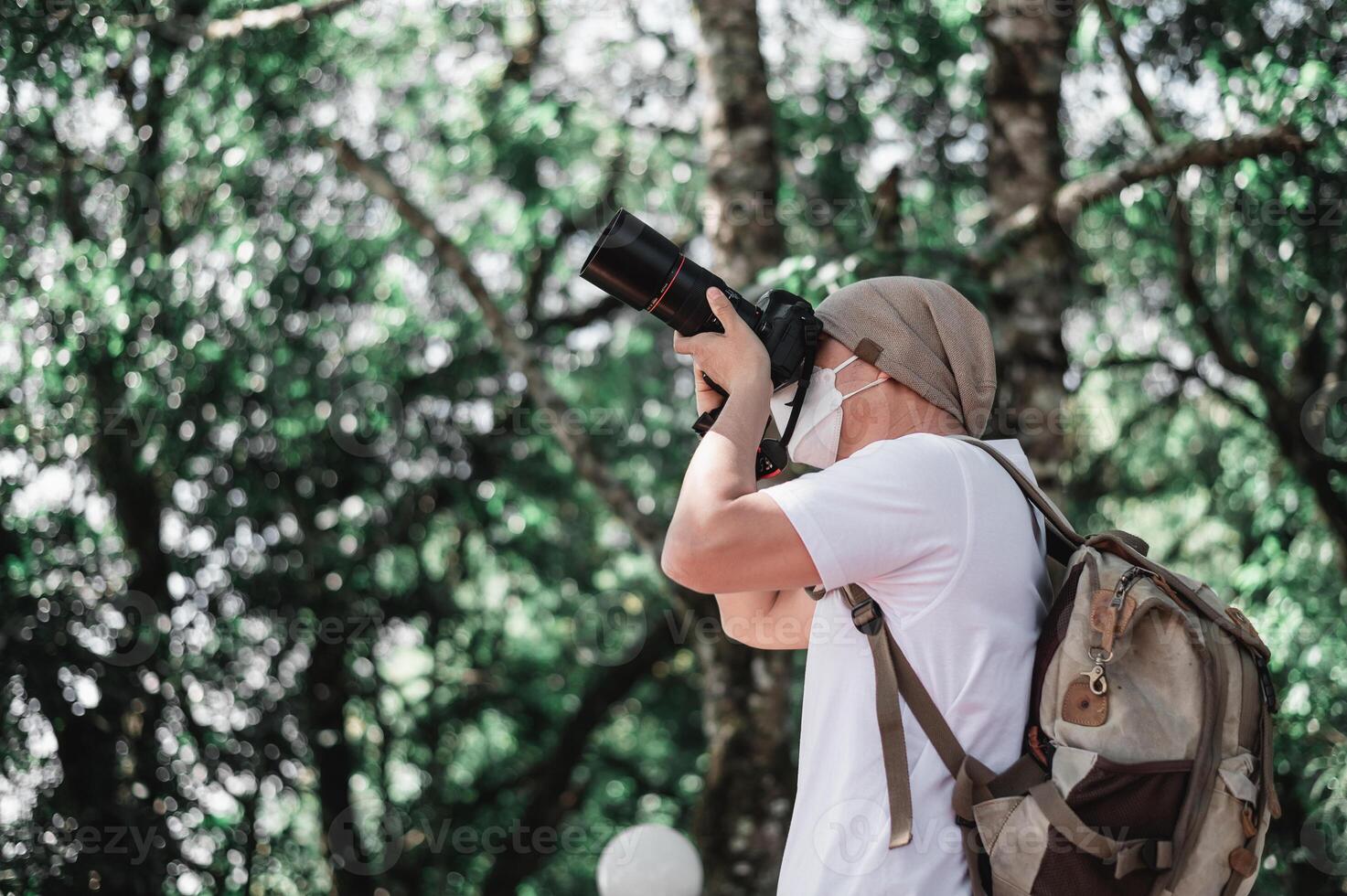 hombre viajero asiático con mochila tomando una foto en el parque