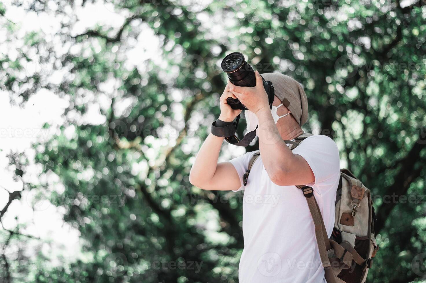 Asian traveler man with backpack taking a photo in the park