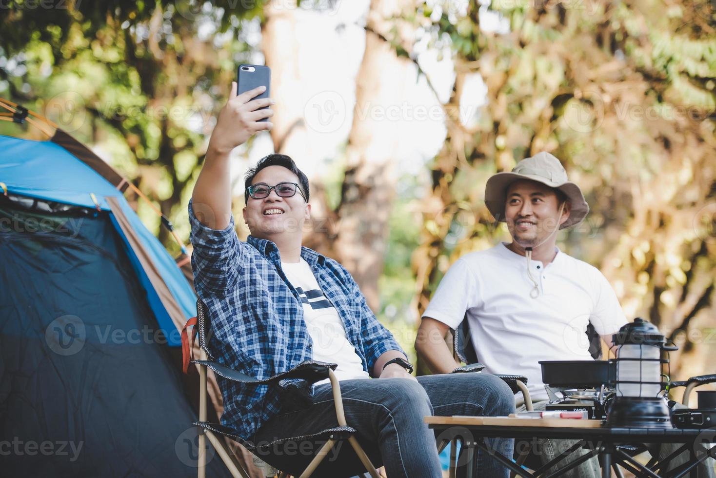 Portrait happy Asian man friends Making a video call with smartphone in camping photo