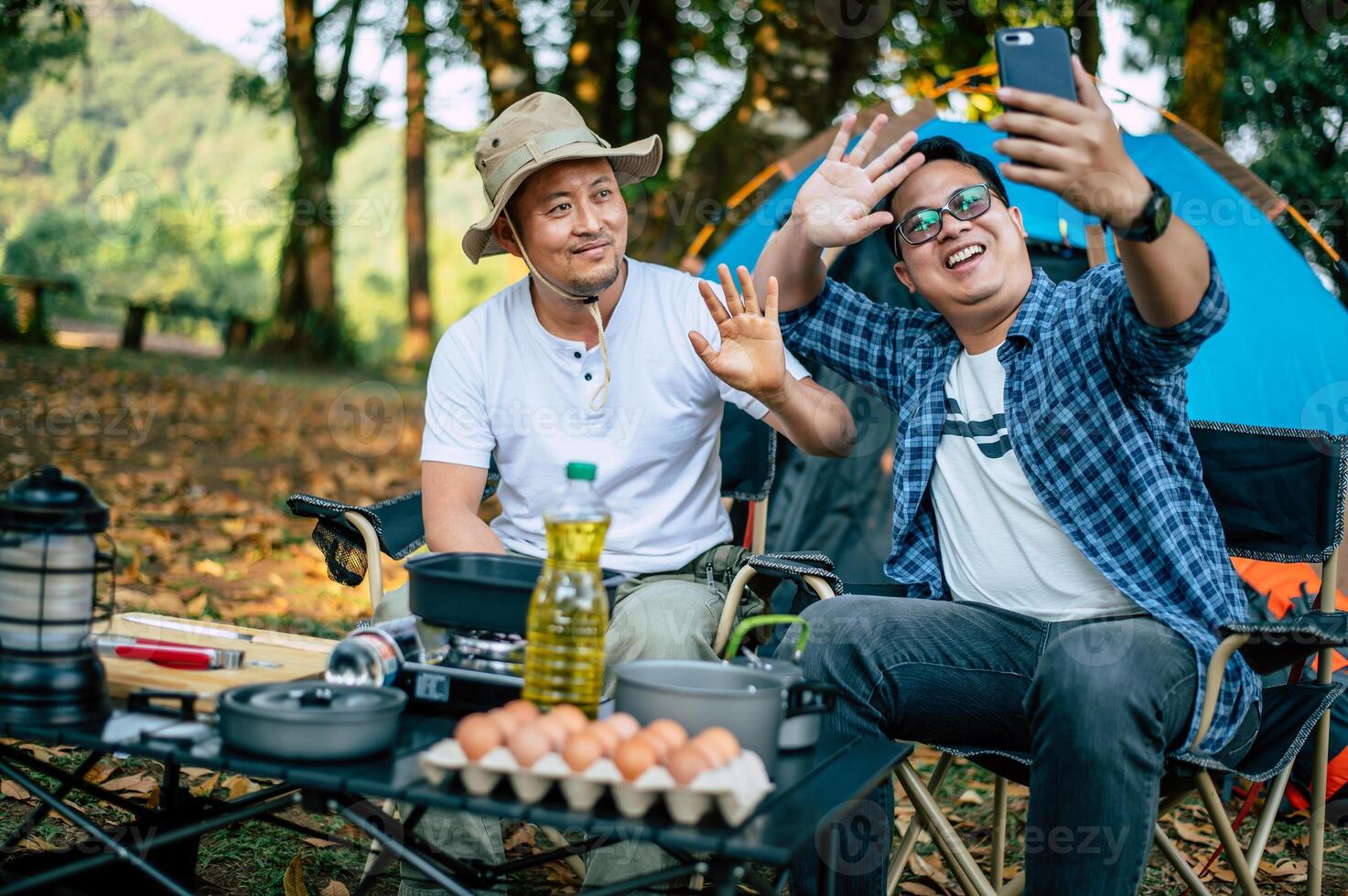 Portrait happy Asian man friends Making a video call with smartphone in camping photo